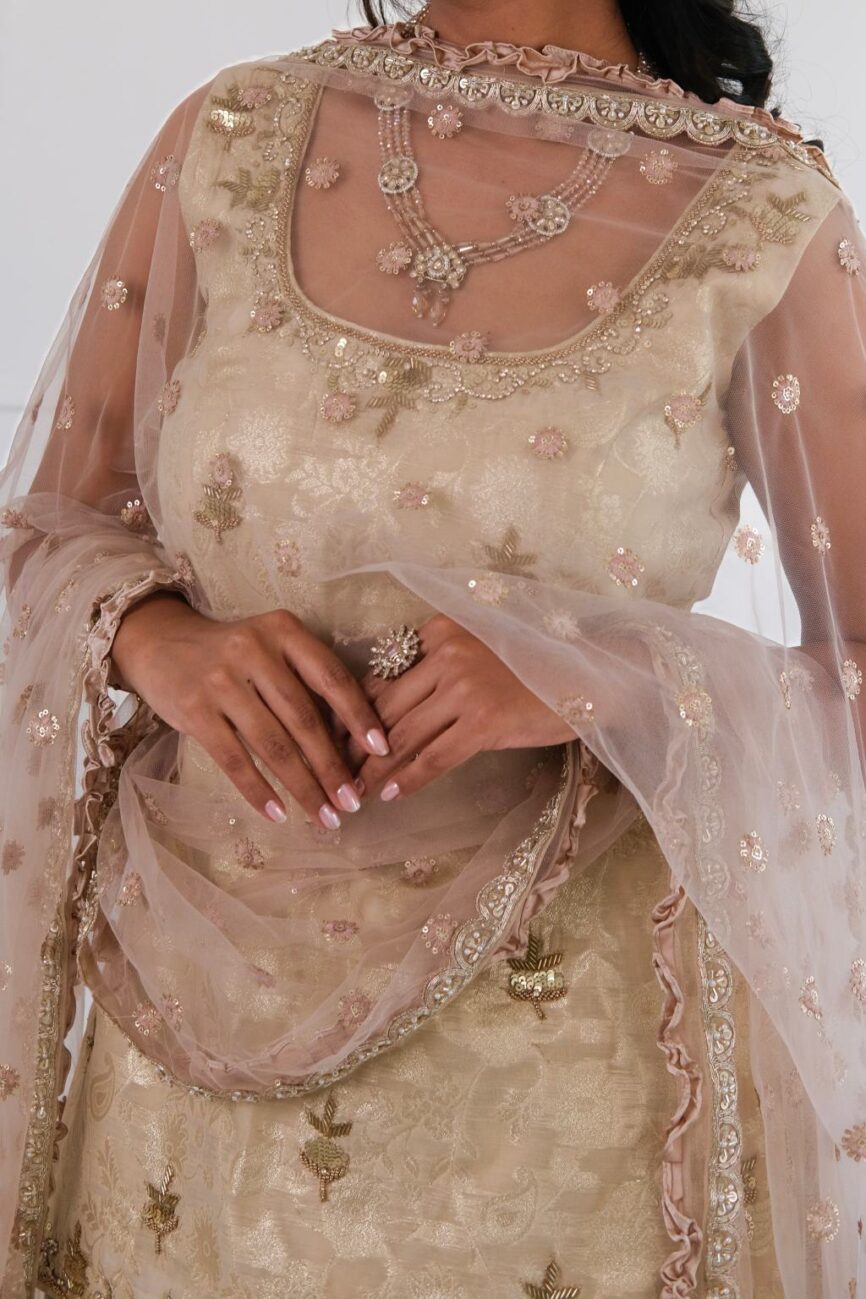 Close-up of delicate hand embroidery on ivory Banarasi lehenga kurta set.
